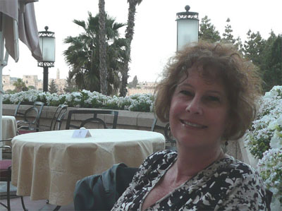 Carol on the balcony of the King David Hotel. The ancient wall of Old Jerusalem is in the background.