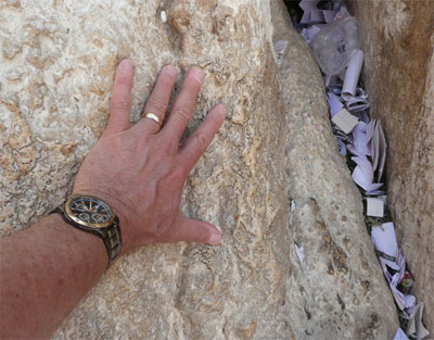 My hand on the stones of the Western Wall, near some prayers